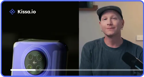 Video frame with a man, smiling next to a close-up of a purple smartphone camera with four lenses.